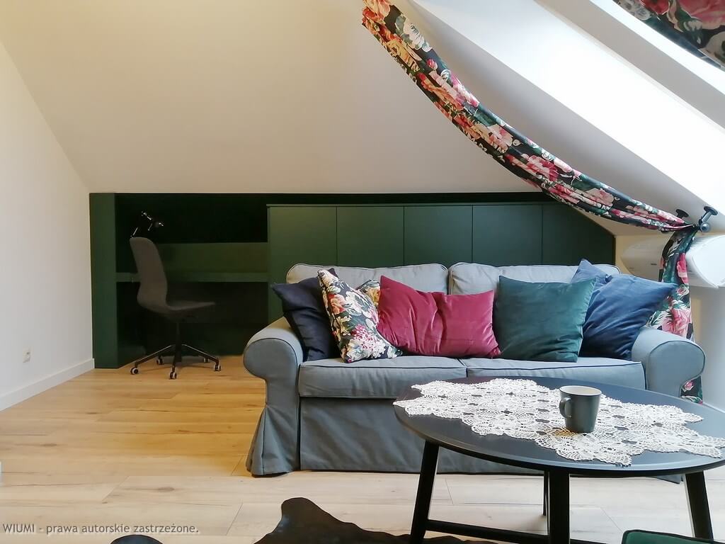 Projektant wnętrz Wrocław pokazuje na fotografii zielona meblościanka w pokoju poddasze