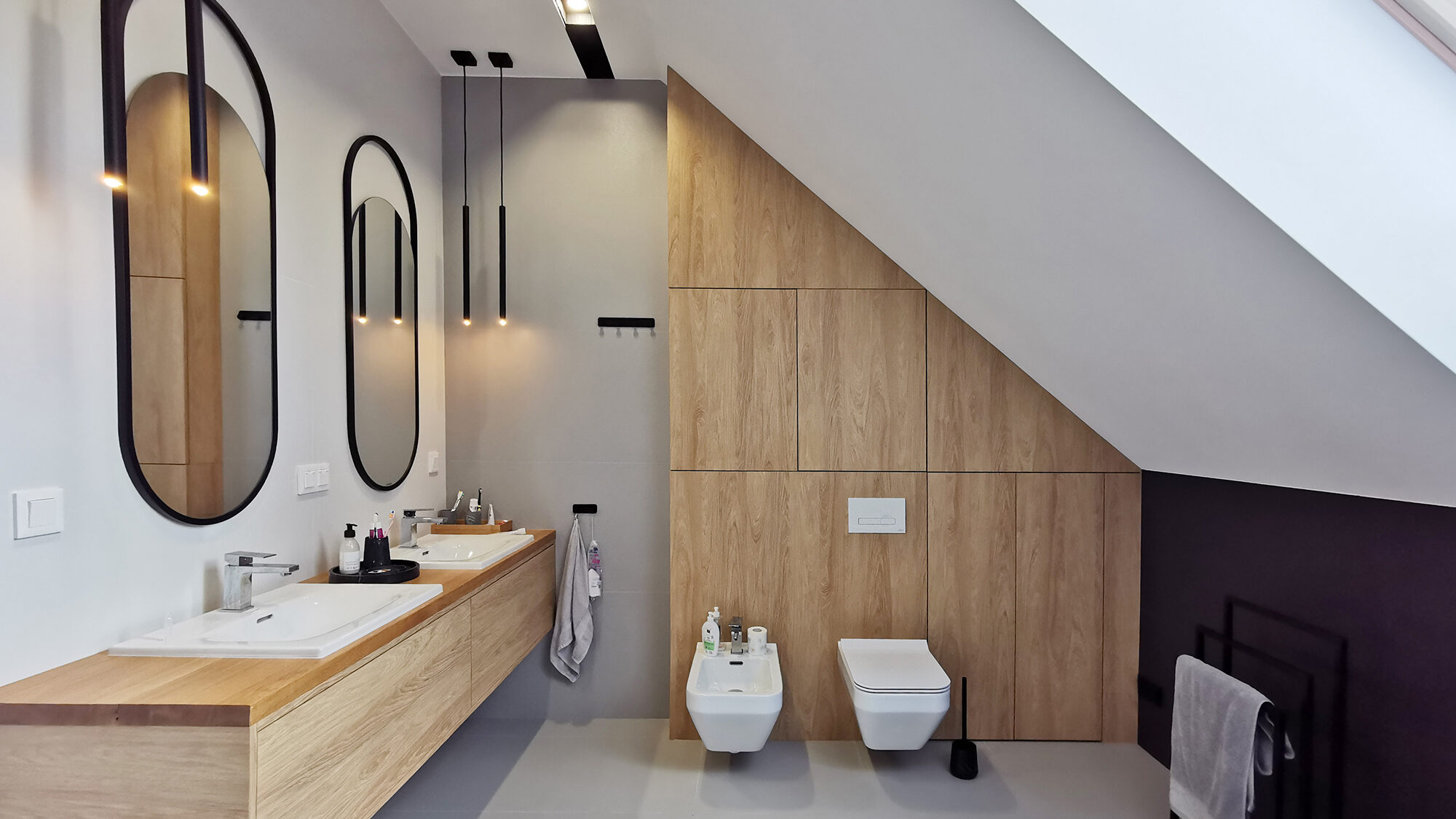 Projektowanie wnętrz Wrocław WIUMI przedstawia łazienkę z dwoma lustrami i umywalkami oraz ubikacją i bidetem.