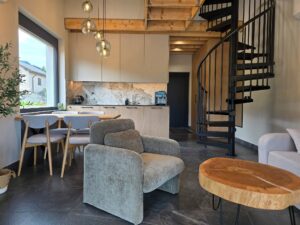 1000059725 salon z kuchnią i schodami kręconymi zaprojektowany przez architekta wnętrz WIUMI